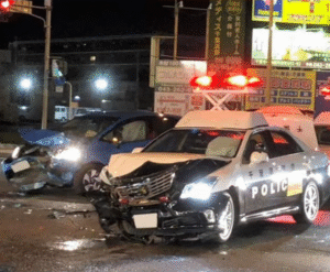 Crumpled police vehicle and damaged blue car at a nighttime intersection crash site, with flashing lights illuminating the scene, following a high-speed pursuit as the Suspect Identified After High-Speed Police Chase Ends in Crash on I-285, according to 2025 reports.